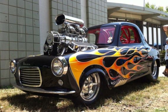a retro car with a flame paint job and an oversized engine that sticks up out of the hood