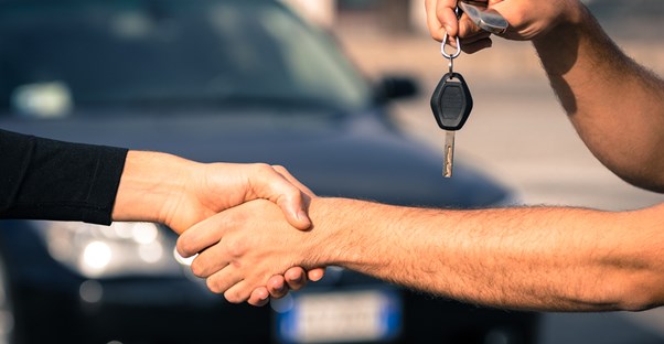 two people shake hands after making a deal at a car auction