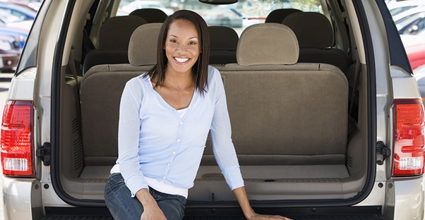 a woman sits on the tailgate of her new minivan
