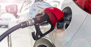 a gas pump handle inserted into a fuel efficient car