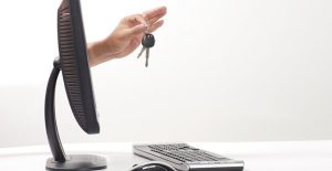 a hand reaches out of a monitor holding car keys symbolizing buying a car online