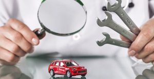 a person examining a toy car with a magnifying glass symbolizing a car warranty