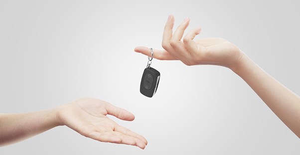an individual hands car keys over to another symbolizing a refinanced auto loan