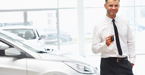 a car salesman offering car keys after a successful car loan