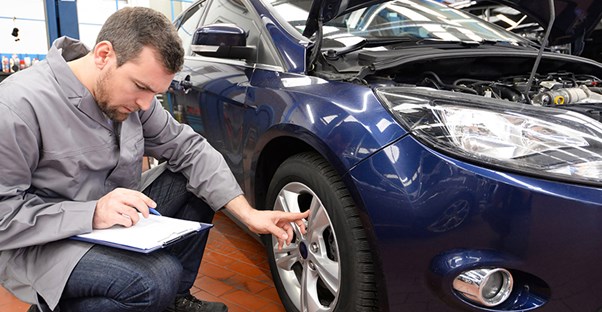 a man examines a car to determine trade in value