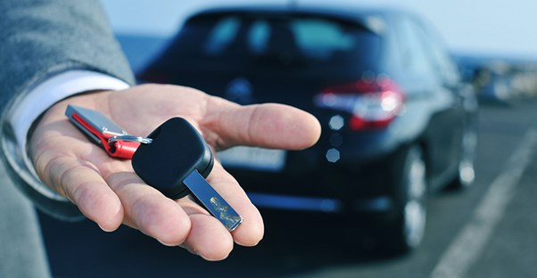 a salesman holds new car keys in his hand