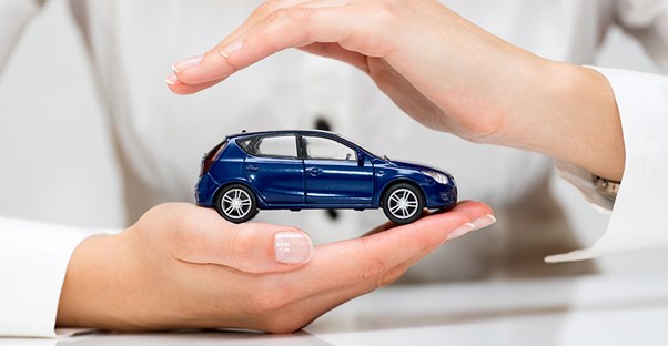 a person holds a toy car symbolizing auto insurance