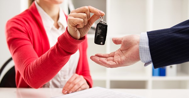 a woman hands a man car keys after explaining auto term length