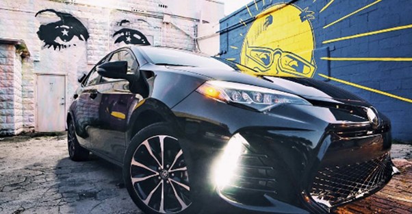 a black 2017 toyota corolla in a painted alley