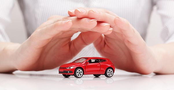 a person holding hands over a car symbolizing auto insurance