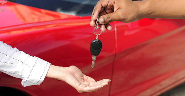 a car dealer hands over car keys to a buyer symbolizing auto insurance