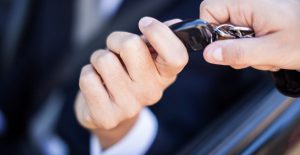 a salesman hands over car keys to a driver after leasing the car
