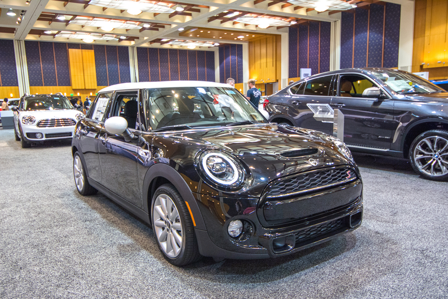 an eggplant colored 2019 mini cooper with a white hard top at an auto show