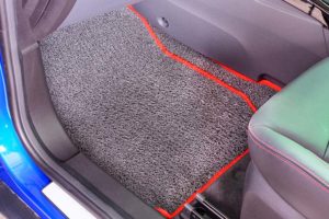 a gray floor mat with a red outline in the driver foothold of a car