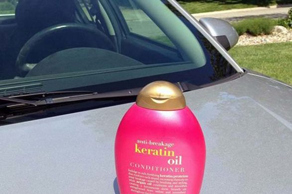 a bottle of hair conditioner sitting on the hood of a car