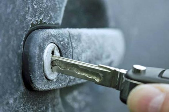 a key being inserted into a frozen car door handle