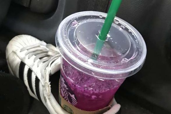 a starbucks drink sitting in a shoe as if it were a cupholder