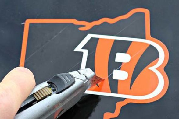 a razor blade removing a decal from a car