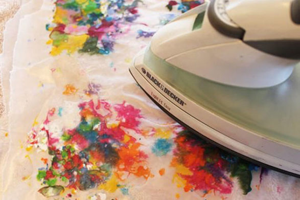 an iron being used on thermal paper to soak up crayons