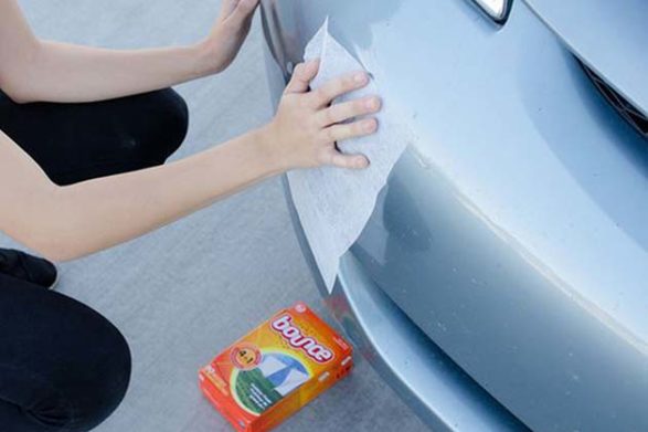 dryer sheets being used to remove bug residue from the front of a car
