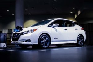 a white 2019 nissan leaf charging at an auto show