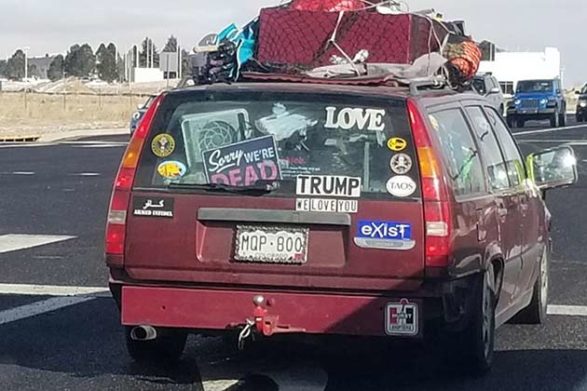 a car with many bumper stickers one of which says sorry were dead