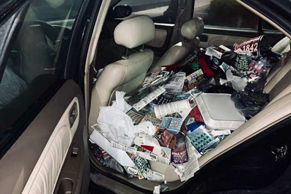 a car filled with trash in the back seat and falling out of the rear door