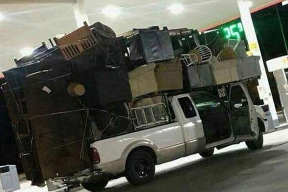 a truck with a comical amount of things piled into the bed and on top of the vehicle