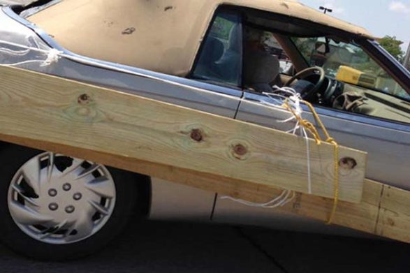 an old convertible with planks of wood tied to the side to simulate wood paneling
