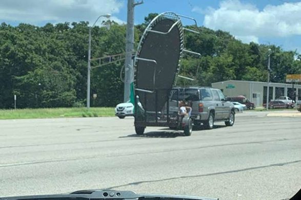 an suv pulling a trailer that had an oversized trampoline on it