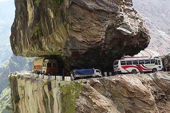 vehicles travel under large rocks along the karnali highway in india