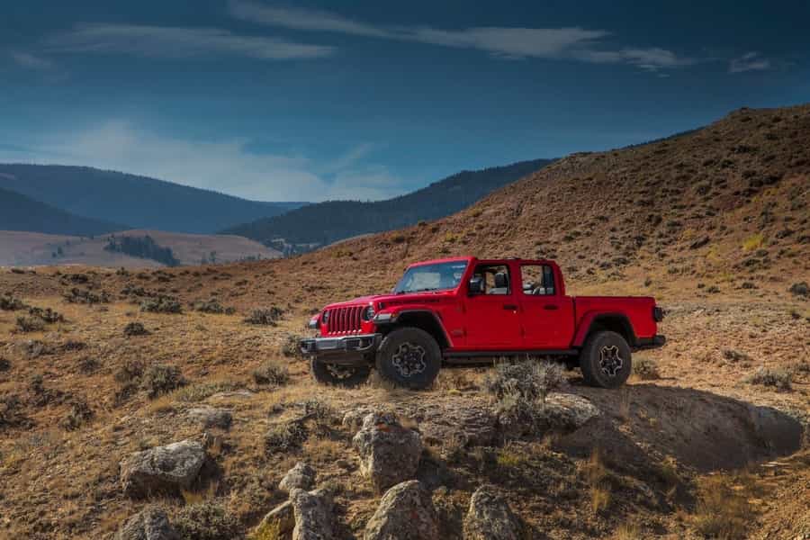 a red 2020 jeep gladiator oh a rocky mountain in the middle of the desert
