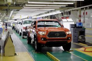an orange toyota tacoma on the assembly line