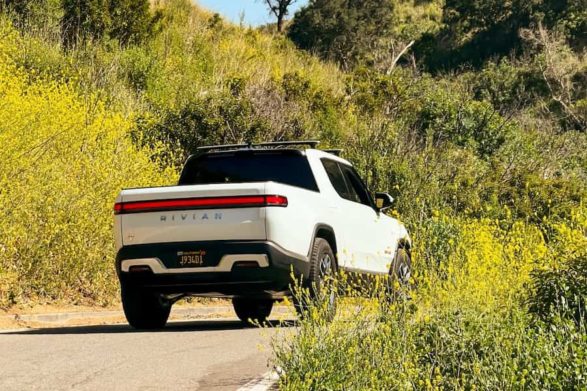 a white rivian r1t drives away from the camera