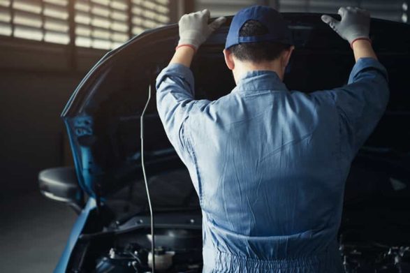 a mechanic raises a car hood to examine the engine