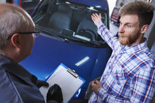 a customer motions to his car as he explains the problem to a mechanic