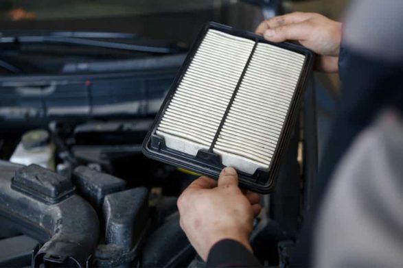 holding a air filter in front of a car engine