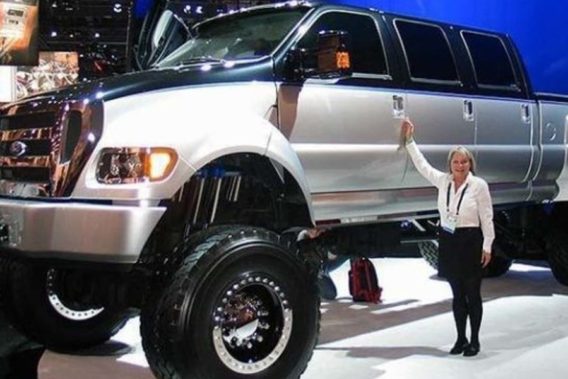 an oversized ford f-150 that towers over a woman standing next to it for scale