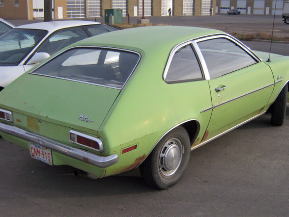 a lime green ford pinto parked in a space at a parking lot