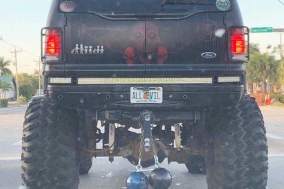 a lifted SUV with skull painted on it and license plate that says ALL EVIL but also has stickers of a family denoting six members