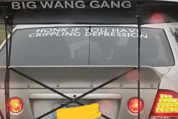 a car that has window lettering saying honk if you have depression but also a giant spoiler saying big wang gang
